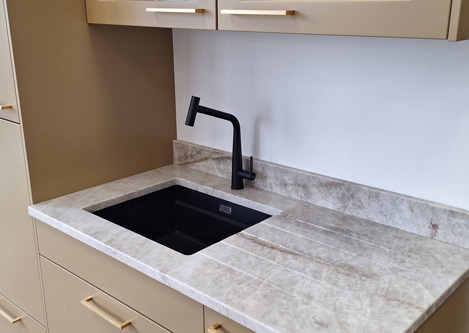 Plan de travail en Granit Taj Mahal dans une petite cuisine en Gironde avec un mitigeur noir et une cuve sous plan noire à Biganos