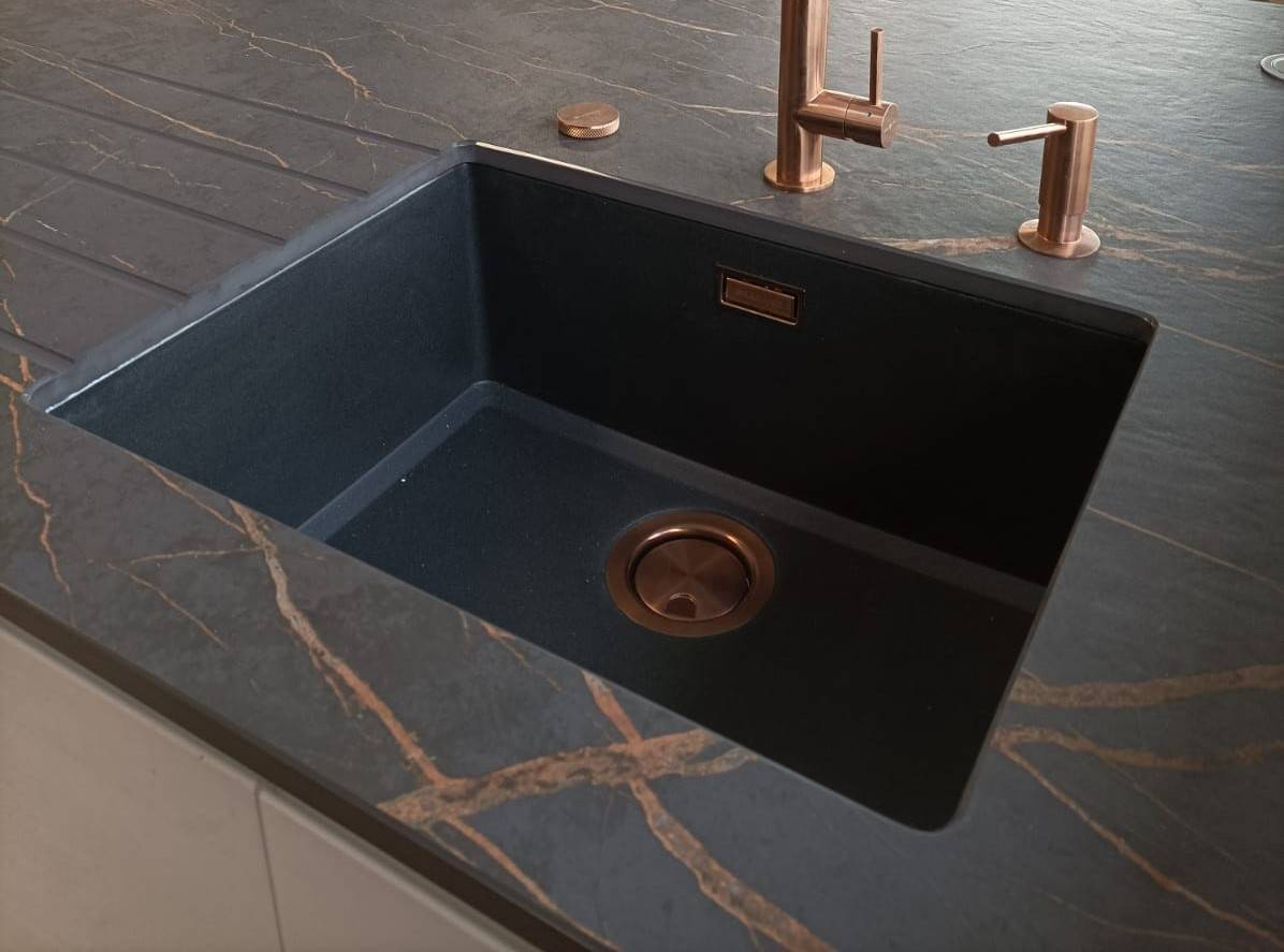 Mélanger des plans de travail noir avec des accessoires laiton dans une cuisine près de Bordeaux